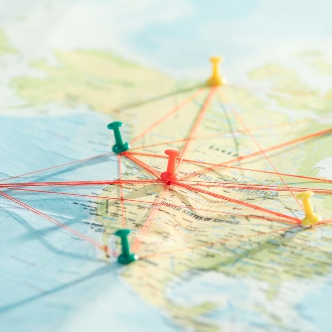 Selective focus of push pins and strings on world map